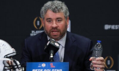 Ole Miss Rebels coach Pete Golding on the stage at a press conference with Miami Hurricanes coach Mario Cristobal