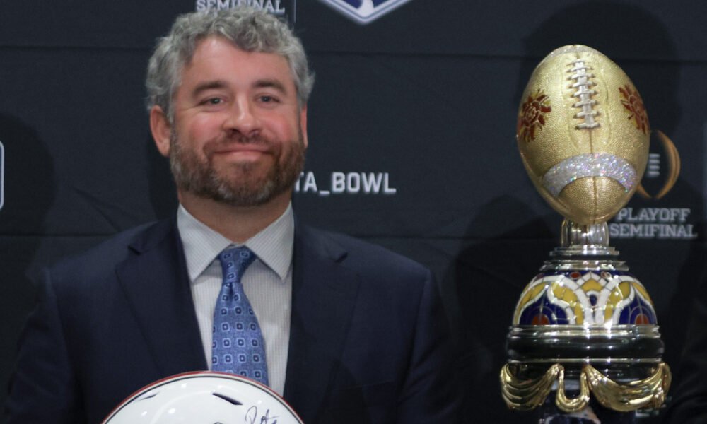 Ole Miss Rebels coach Pete Golding on the stage at a press conference with Miami Hurricanes coach Mario Cristobal