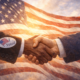 Two men in suits shake hands in front of an American flag, one wearing an “I Voted” sticker, symbolizing unity and civic responsibility.